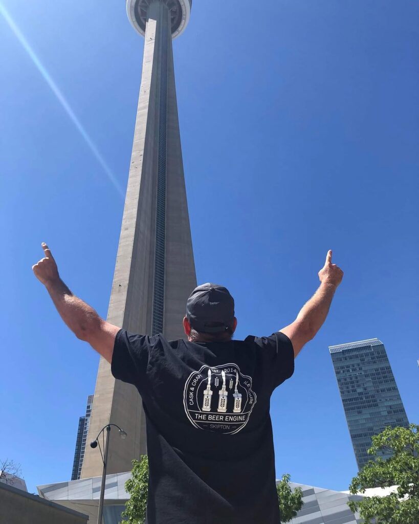 The Beer Engine x J Mitchell Design 1 Person wearing The Beer Engine Skipton t-shirt in front of the CN Tower in Toronto