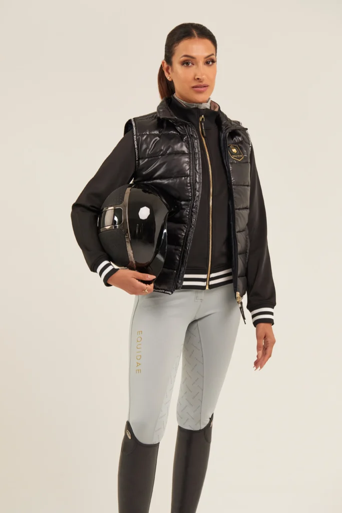 equestrian fashion designer Equidae london Model wearing full Equidae London outfit designed by Jonathan Mitchell, holding a riding helmet.