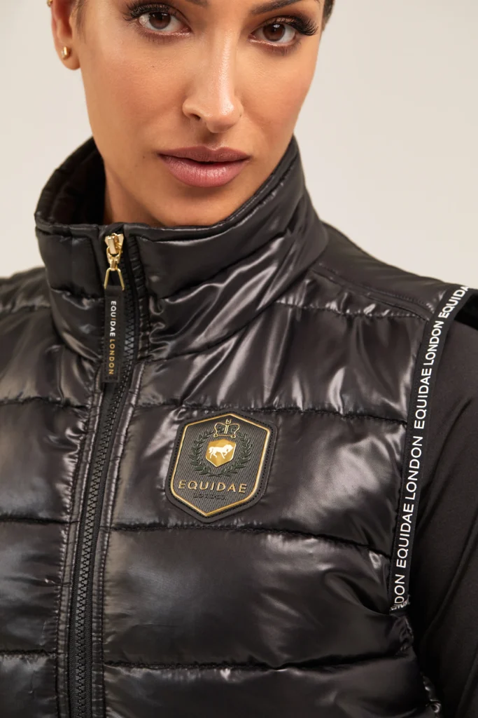 equidae-london-black-gilet-fashion-detail-jmitchelldesign Close-up of black padded Equidae London gilet with gold crest and branded trims, designed by Jonathan Mitchell