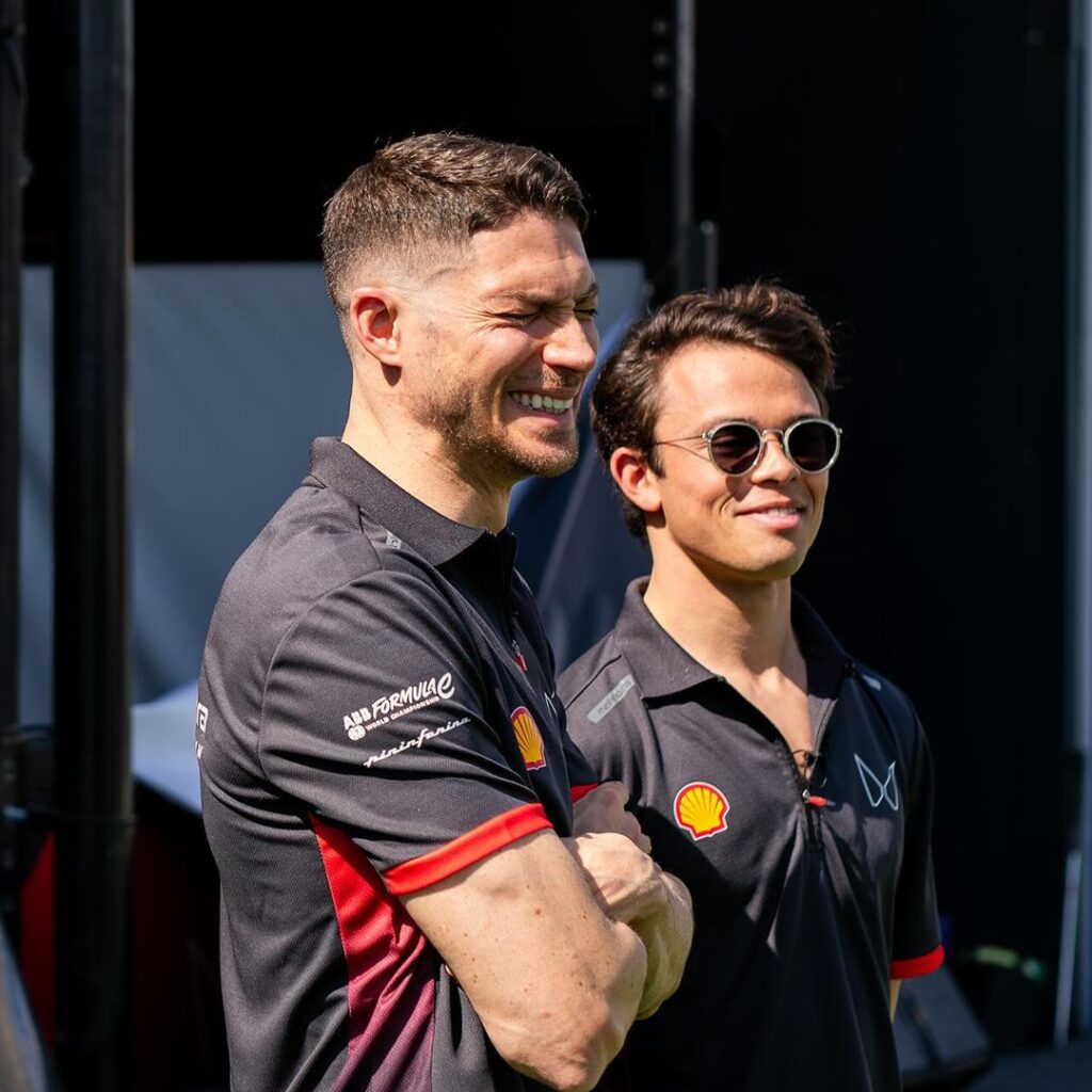 Mahindra Formula E Polo Shirt – Collaborative Garment Design Mahindra Racing team members smiling in matching black polo shirts with red accents and sponsor logos