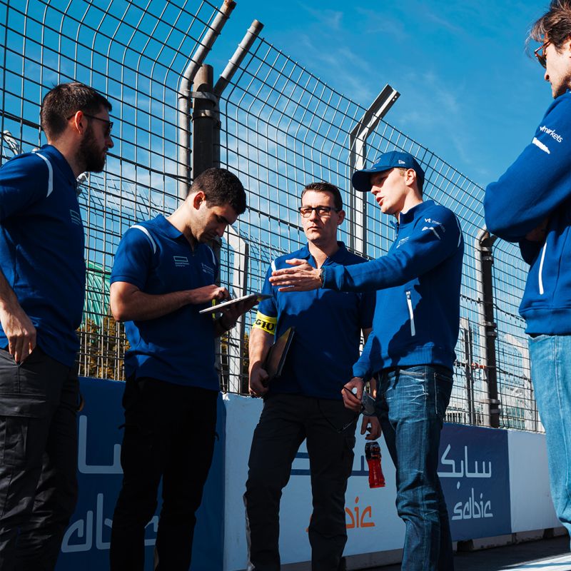 Maserati motorsport teamwear group discussion Maserati MSG Racing team members wearing branded teamwear discussing trackside