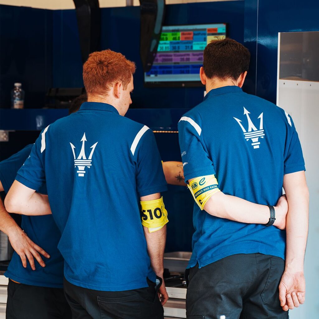 Maserati MSG Racing Formula E Team Polo Shirts Two Maserati MSG Racing team members wearing blue Formula E teamwear polo shirts with large back logo