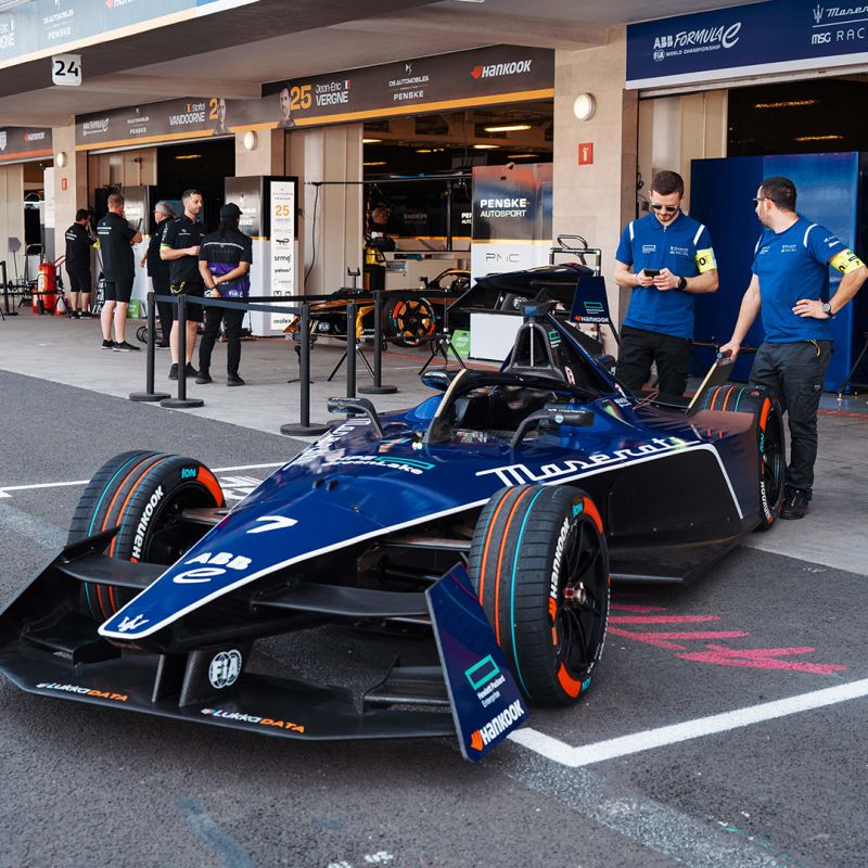 Maserati MSG Racing – Team Activewear in the Paddock Team members in matching blue Maserati MSG Racing uniforms beside a Formula E car