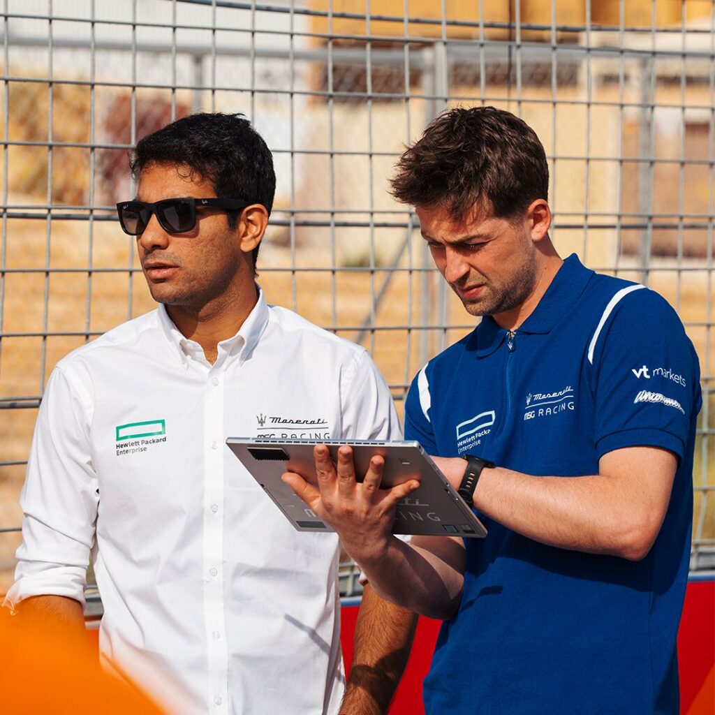 Maserati Racing – White Shirt and Blue Polo Teamwear Two Maserati MSG Racing team members reviewing data, wearing branded white shirt and blue polo
