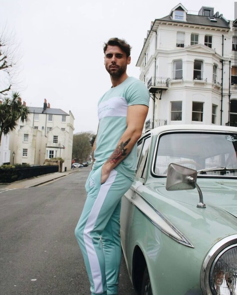 scar-tissue-mint-green-set-city-streetwear Male model in a mint green Scar Tissue T-shirt and joggers leans against a vintage mint car on a residential city street.