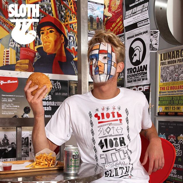 sloth clothing brighton mens streetwear t-shirt designer Man with geometric face paint wearing Sloth Clothing graphic T-shirt eating a burger in a Brighton venue