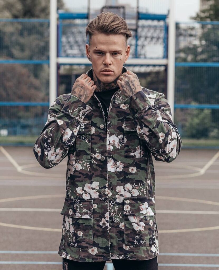 streetwear-fashion-designer-menswear-camo-floral-jacket-jmitchelldesign Male model wearing a camo floral streetwear jacket designed by Jonathan Mitchell on an urban basketball court