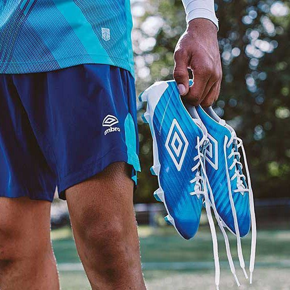 umbro-manchester-football-training-apparel-designer Footballer holding Umbro boots in blue shorts and kit designed by Jonathan Mitchell