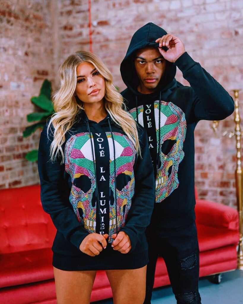 vole-la-lumiere-hoodies-colour-skull-print Male and female models wearing black hoodies with colourful skull graphic and Volé La Lumière slogan