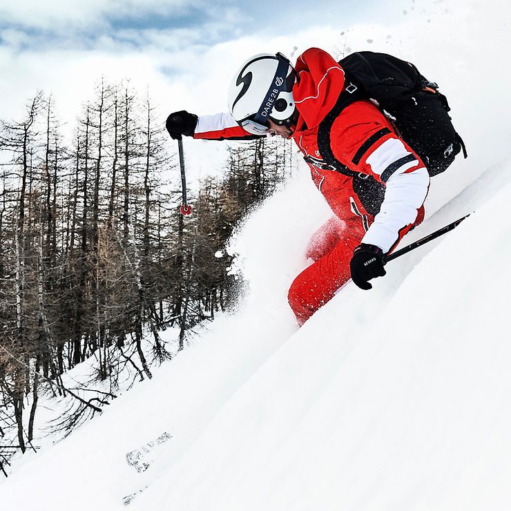 Skier in red Dare2b outfit speeding through powder snow, designed by J Mitchell Design